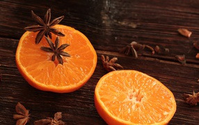 Две половины апельсина на деревянном столе с бадьяном