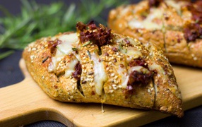 Булочка с кунжутом и сыром на разделочной доске 