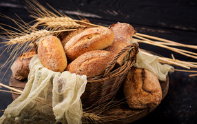 Fresh pastries in a basket on a table with wheat ears