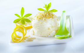 A ball of lemon ice cream with pistachios with a green spoon