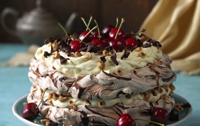 A beautiful cream cake with chocolate and cherries and nuts