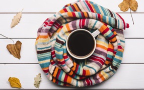 A cup of hot chocolate on a table with a knitted scarf