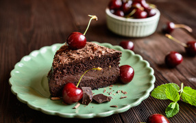 A piece of cake with cherries on a plate