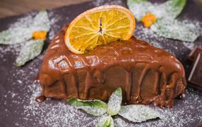 A piece of cake with chocolate and a slice of orange