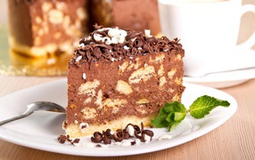 Кусок торта с шоколадом и листьями мяты на тарелке