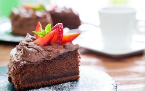 A piece of cake with chocolate cream and pieces of ripe strawberries
