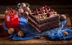 Кусок шоколадного торта на столе с вишнями и грецкими орехами