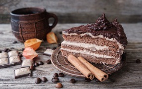 Кусок торта с корицей на столе с шоколадом и чашкой кофе