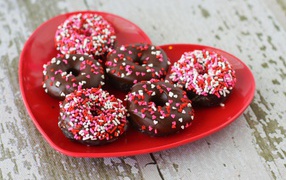 Appetizing donuts on a red plate in the shape of a heart
