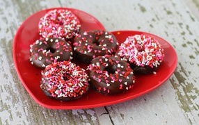 Аппетитные пончики на красной тарелке в форме сердца