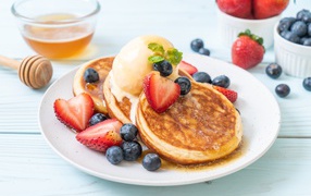 Appetizing fritters with ice cream, honey and berries of strawberries and blueberries
