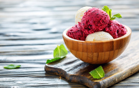 Шарики фруктового и ванильного мороженого в деревянной миске на столе