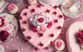 Красивый праздничный розовый торт в форме сердца украшен цветами