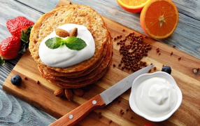 Buckwheat pancakes with sour cream on a cutting board