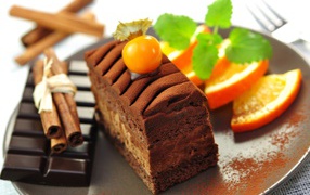 Пирожное с шоколадом, корицей и кусочками апельсина на тарелке