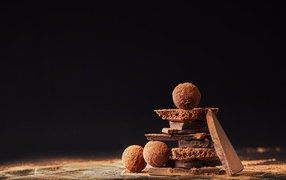 Шоколадные шарики и кусочки шоколада на черном фоне