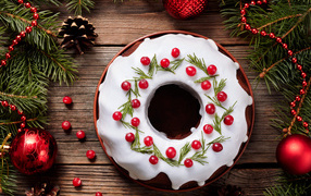 Рождественский пирог с ягодами клюквы на деревянном столе с еловыми ветками