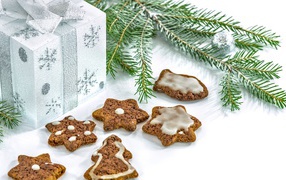 Новогоднее печенье с подарком и еловой веткой на белом фоне