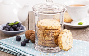 Печенье в стеклянной банке на столе с орехами и черникой