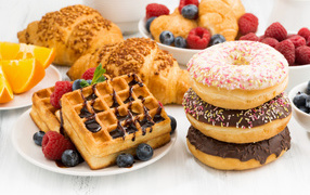 Croissants, waffles and donuts on a table with berries