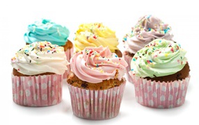 Кексы с разноцветным кремом на белом фоне