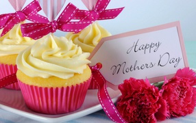 Кексы с кремом рядом с гвоздиками и пожеланиями к Дню матери