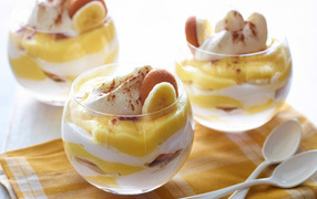 Десерт с бананами и печеньем в стаканах на столе 
