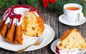 Праздничный кекс с глазурью на столе с чашкой чая