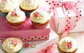 Праздничные кексы с кремом и подарочной коробкой на столе