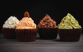 Four delicious cupcakes with cream on a black background