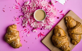 Fresh croissants on a table with a cup of cocoa and chrysanthemum flowers