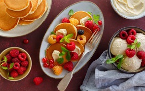 Оладьи на столе с ягодами малины и мороженым