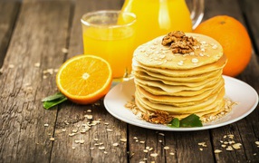 Оладьи с орехами на столе с апельсиновым соком и апельсинами