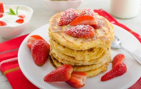Pancakes with strawberries and powdered sugar on a white plate