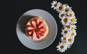 Оладьи с клубникой на тарелке на сером фоне с ромашками