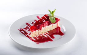 Piece of cake with strawberries and jam on a white plate