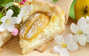 Кусок пирога с яблоками на деревянной лопатке с цветами яблони