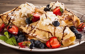 Sweet pancakes with cream, berries of strawberries and blueberries