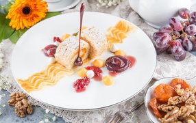 Сладкий рулет с сухофруктами и джемом на тарелке 