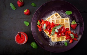 Sweet waffles with strawberries and powdered sugar on a plate