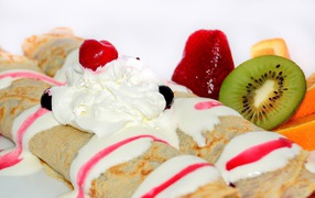 Thin pancakes with cream, strawberries and kiwi