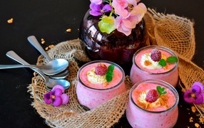Три банки десерта с малиной на столе с цветами