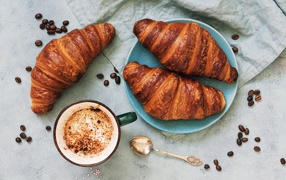 Три круассана на столе с чашкой кофе