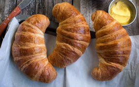Three fresh croissants on a table with cream