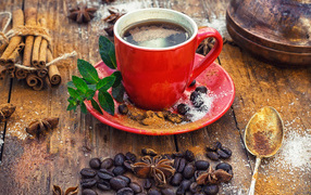 A cup of coffee on a table with grains, cinnamon and bean grains