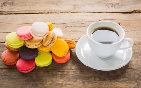 A cup of coffee on a table with multicolored macaroons