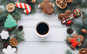 A cup of coffee on a wooden table with ginger cookies, fir branches and decor