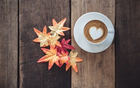 Чашка кофе на деревянном столе с желтыми листьями