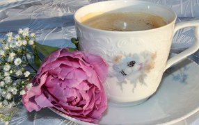 A cup of coffee with a pink peony flower and white flowers