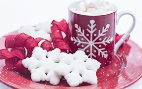 A cup of hot chocolate with marshmallows on a plate with snowflakes